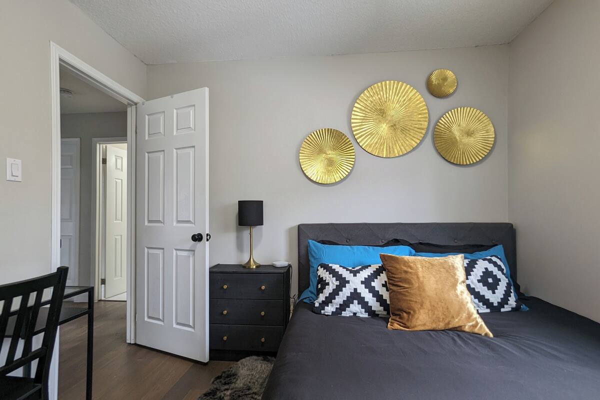 A bedroom with a bed, bedside table, lamp, and decorative wall art.