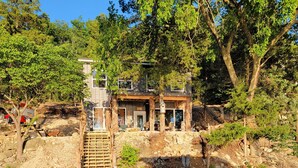 A wooden bridge leading to a rustic cabin with a stone wall and a small wooden deck. - Stay, Play, Getaway. Beautiful Lake Front Home-Large private dock  (Rocky Mount)