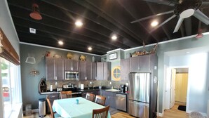 A modern kitchen with dark ceiling beams, stainless steel appliances, and a dining area with a table and chairs. - Stay, Play, Getaway. Beautiful Lake Front Home-Large private dock  (Rocky Mount)