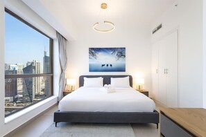 A hotel room with a large window, a bed, bedside tables, a wooden bench, and a city view.