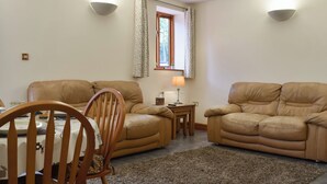 Ein Wohnzimmer mit zwei beigefarbenen Sofas, einem Holzessttisch und einem Teppich.