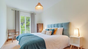 Une chambre à coucher comprenant un lit, une table de chevet, une chaise, une armoire et une fenêtre avec des rideaux.