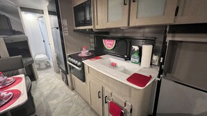 A compact kitchen with a microwave, stove, sink, and cabinets. - “NATURE IN THE CITY” (Orlando)