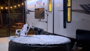 A covered RV with a bed, a small table, and chairs. - “NATURE IN THE CITY” (Orlando)