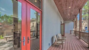 A covered outdoor area with a wooden deck, a red door, and two chairs. - Colorful & Unique Ruidoso Studio Escape in Midtown (Ruidoso)