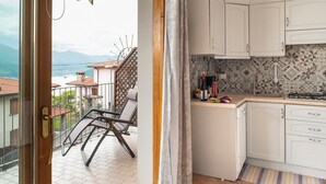 Una cocina con armarios blancos, salpicadero de azulejos y vista al mar.