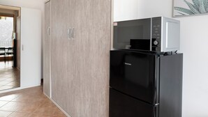 Una cocina con un refrigerador negro, un microondas y un armario de madera.