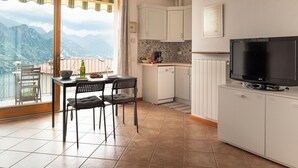 Cocina compacta con comedor, televisor y vistas a montañas.