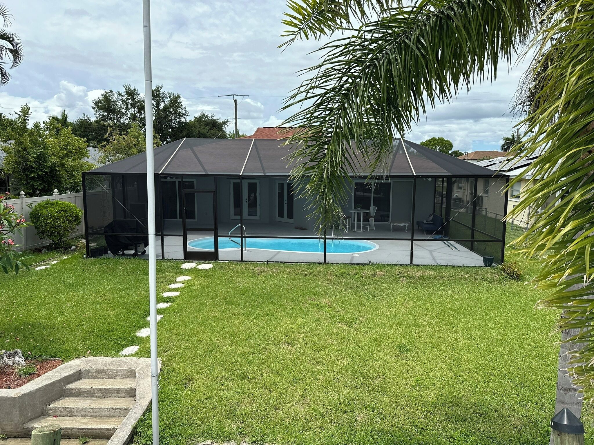 Ein modernes Haus mit Swimmingpool, überdachter Terrasse und gepflegtem Rasen.