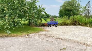 Un sendero de grava que conduce a un carrito azul en un entorno rural.