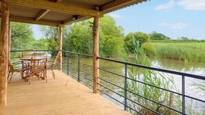 A wooden deck with chairs overlooking a calm river, surrounded by lush greenery. - 1 bedroom accommodation in Boys Hill, near Sherborne (Boys Hill, near Sherborne)