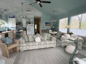 A spacious living area with a sofa, armchairs, and a dining table. There is a kitchen area with cabinets and appliances. The room has large windows and a ceiling fan. - The Tree Top Terrace- is private, close to ocean & downtown on James Island.. (Charleston)