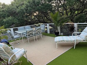 An outdoor patio with a table and chairs, surrounded by a white fence and lush greenery. - The Tree Top Terrace- is private, close to ocean & downtown on James Island.. (Charleston)
