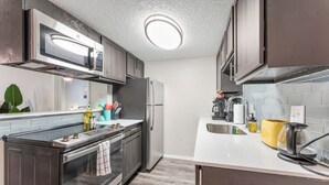 A modern kitchen with stainless steel appliances, a microwave, oven, and a sink. - Soco 2BR Comfy Suite w Pool King bed Fast Wifi (Austin)