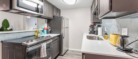 A modern kitchen with stainless steel appliances, a microwave, oven, and a sink.