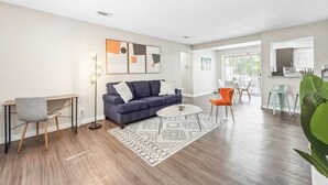 Un salón moderno con un sofá azul, una mesa de centro redonda y una silla gris.