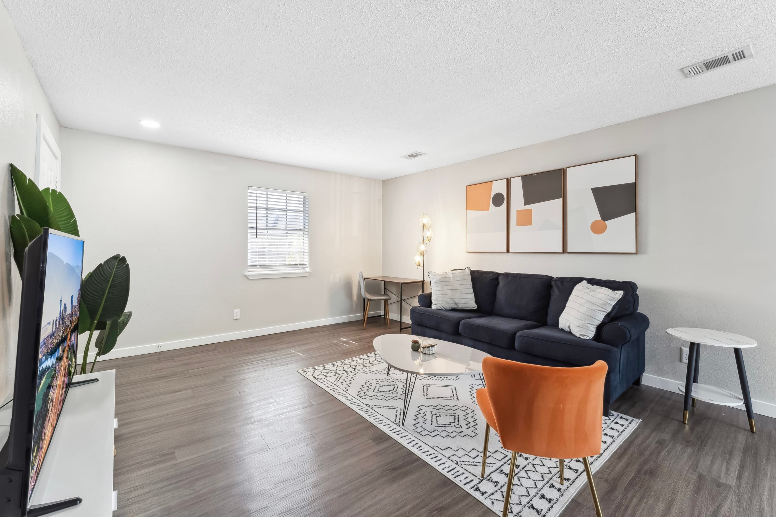 A modern living room with a dark blue sofa, a white coffee table, and a patterned rug.