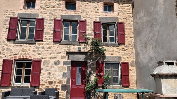 A stone building with red shutters and a green bench in front. - HOUSE 8-9 people LAVAUDIEU, most beautiful village in France. Pets allowed. (Lavadieu)