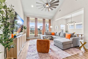 Een moderne woonkamer met een modulaire bank, een glazen salontafel en een grote flatscreen-televisie.
