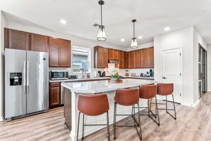 A modern kitchen with stainless steel appliances, wooden cabinets, and a central island with bar stools.