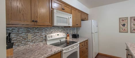 A kitchen with wooden cabinets, a microwave, a stove, and a refrigerator.