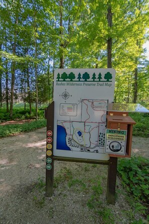 A trail map sign for Rushes Wilderness Preserve Trail with hiking donation information.
