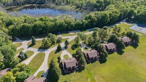 Vue aérienne d’un quartier résidentiel avec de nombreuses maisons, un étang et un court de tennis.