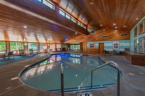 An indoor swimming pool with wooden ceiling beams, clear glass walls, and a tiled floor. - Lakefront 2BR Condo: Balcony, Hot Tub, & Sauna at The Rushes (Baileys Harbor)
