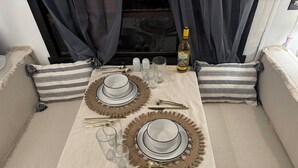 Een eettafel gedekt met witte borden, gouden bestek en glazen, met een fles wijn op tafel.