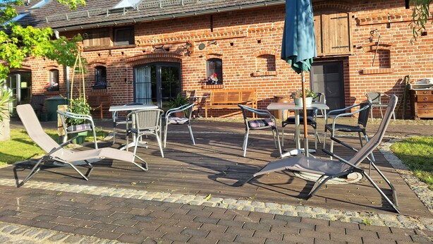 En murstensbygning med en patio med udendørs møbler og en blå parasol.