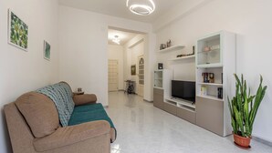 A modern living room with a sofa, a television, and a bookshelf.