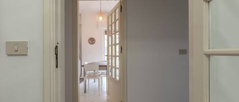 A hallway leading to a dining area with a table and chairs.