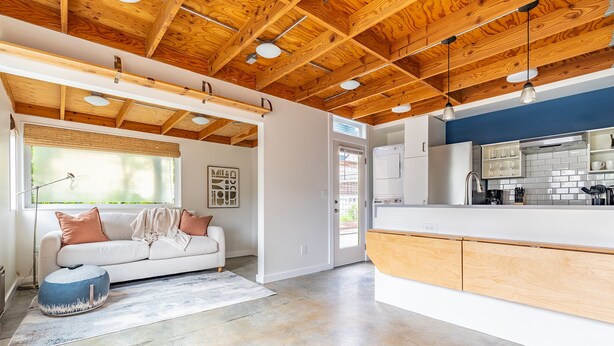 A modern kitchen with wooden beams, a white countertop, and a built-in oven. - Charming Urban Cottage in Cap Hill (Seattle)