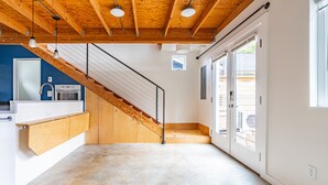 A modern kitchen with a built-in oven, a wooden staircase, and a view of the outside through a glass door. - Charming Urban Cottage in Cap Hill (Seattle)