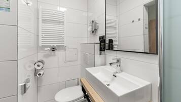 A modern bathroom with a white toilet, a sink, and a mirror.