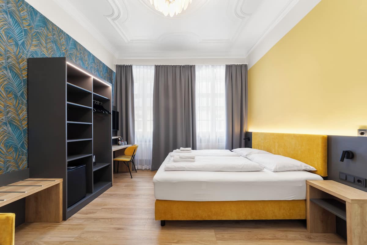 Une chambre d’hôtel comprenant un lit, un bureau, une chaise, une armoire et un téléviseur.