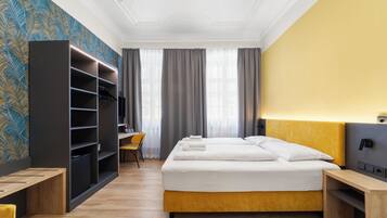 A hotel room with a bed, a desk, a chair, a wardrobe, and a television.