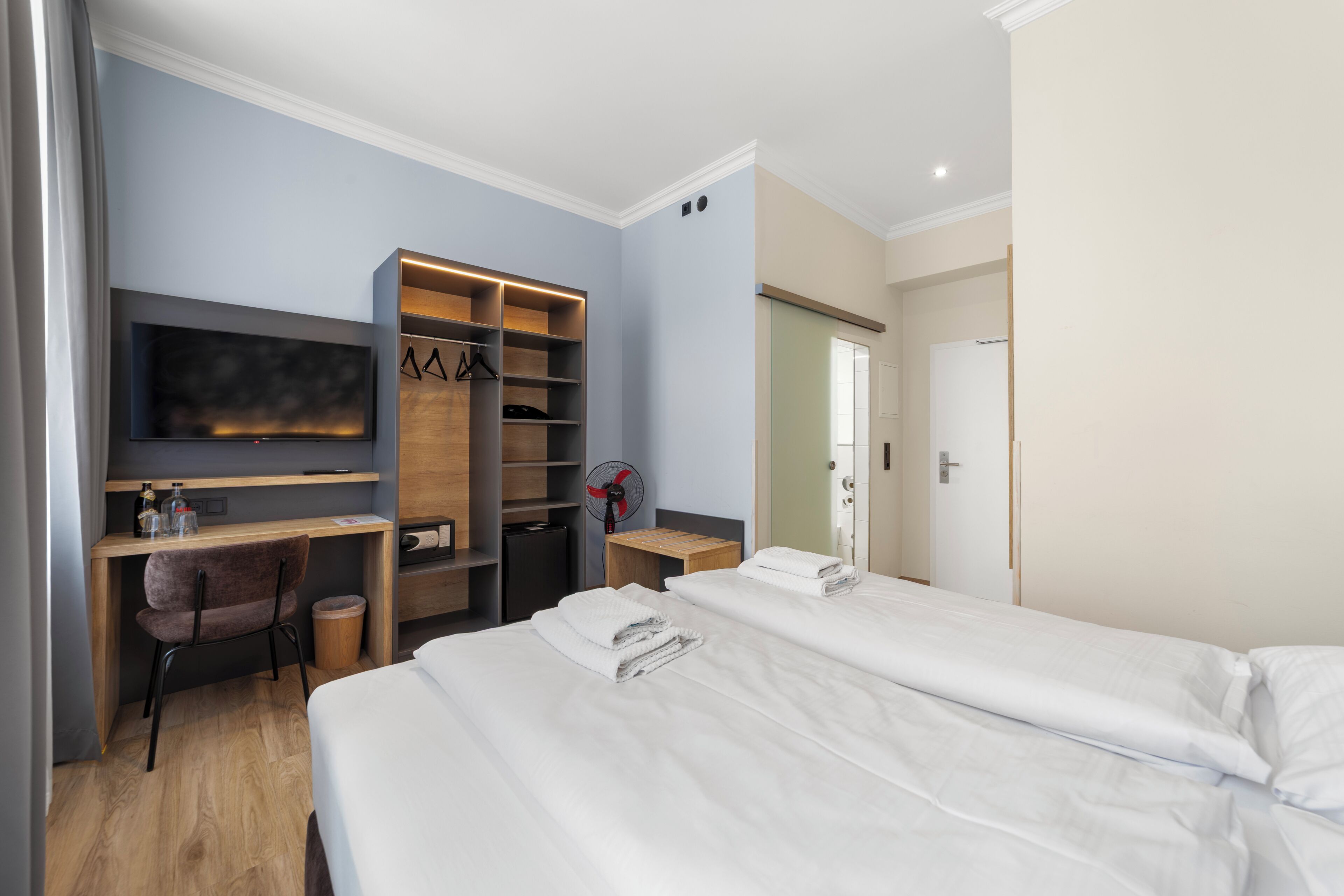 Habitació d'hotel amb llit, escriptori, cadira, televisió i armari.