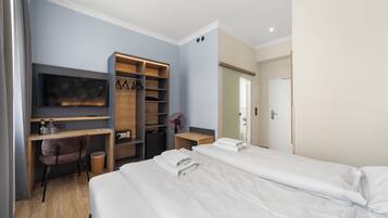 Habitació d'hotel amb llit, escriptori, cadira, televisió i armari.