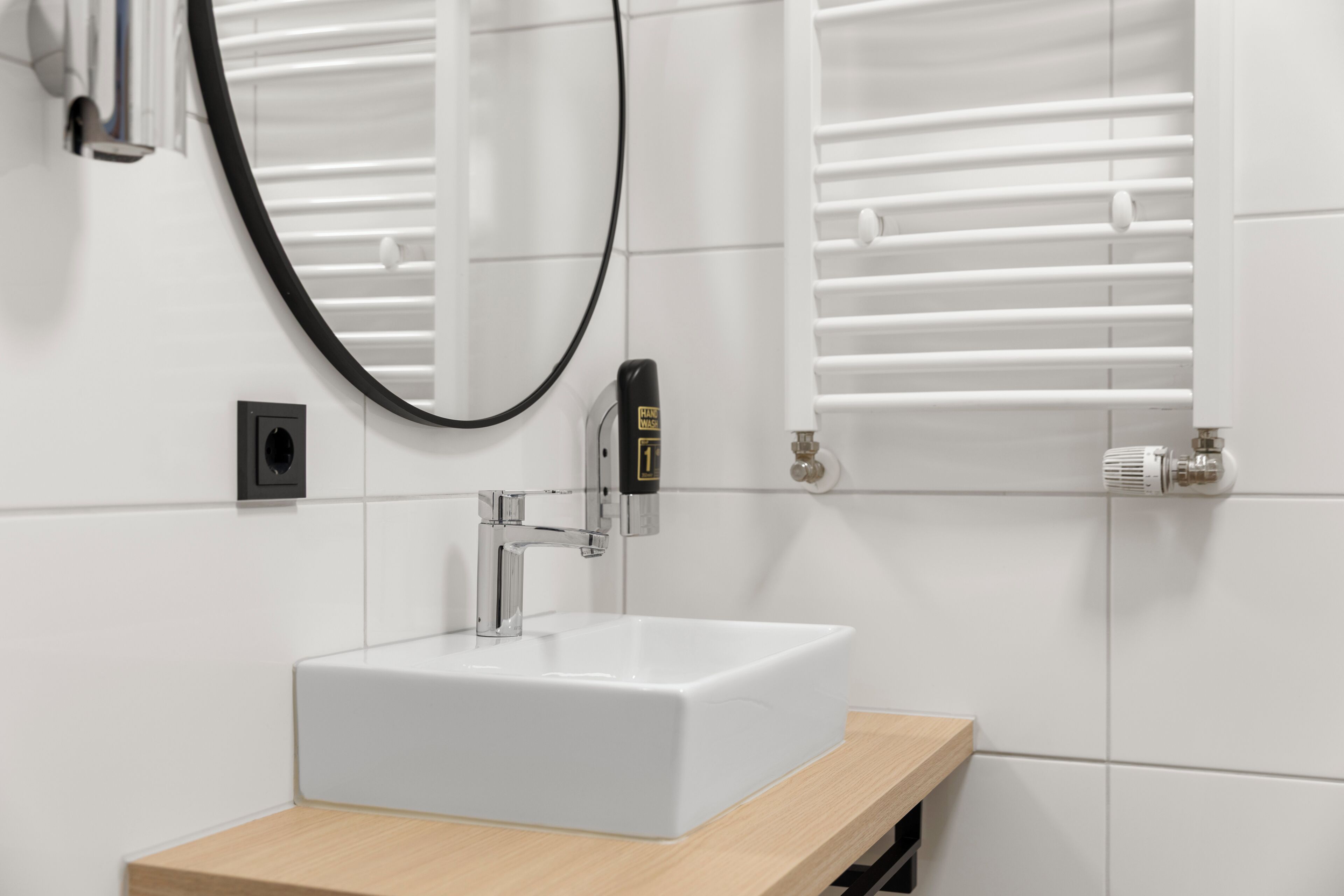 Un baño moderno con lavamanos blanco, espejo y toallero.