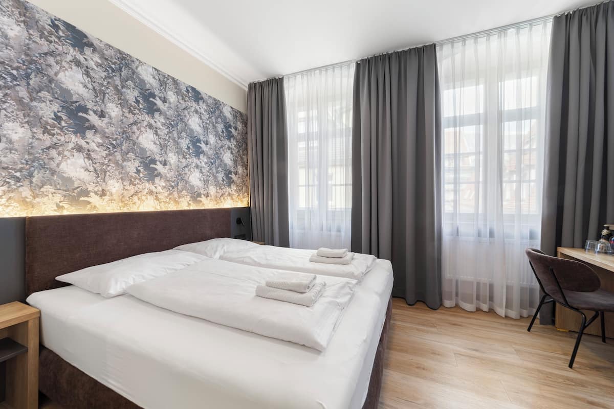 Une chambre d’hôtel avec un grand lit, un bureau et une vue dégagée à travers des rideaux légers.