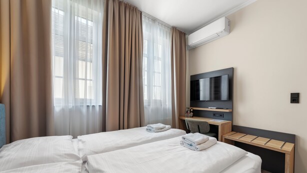 Ein Hotelzimmer mit zwei Betten, einem Fernseher, einem Schreibtisch und einer Klimaanlage.