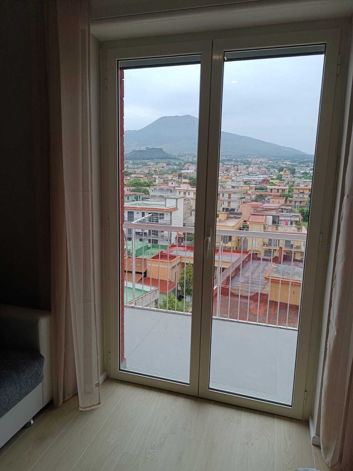 Et værelse med en stor skydedør, der fører ud til en balkon med udsigt over byen.