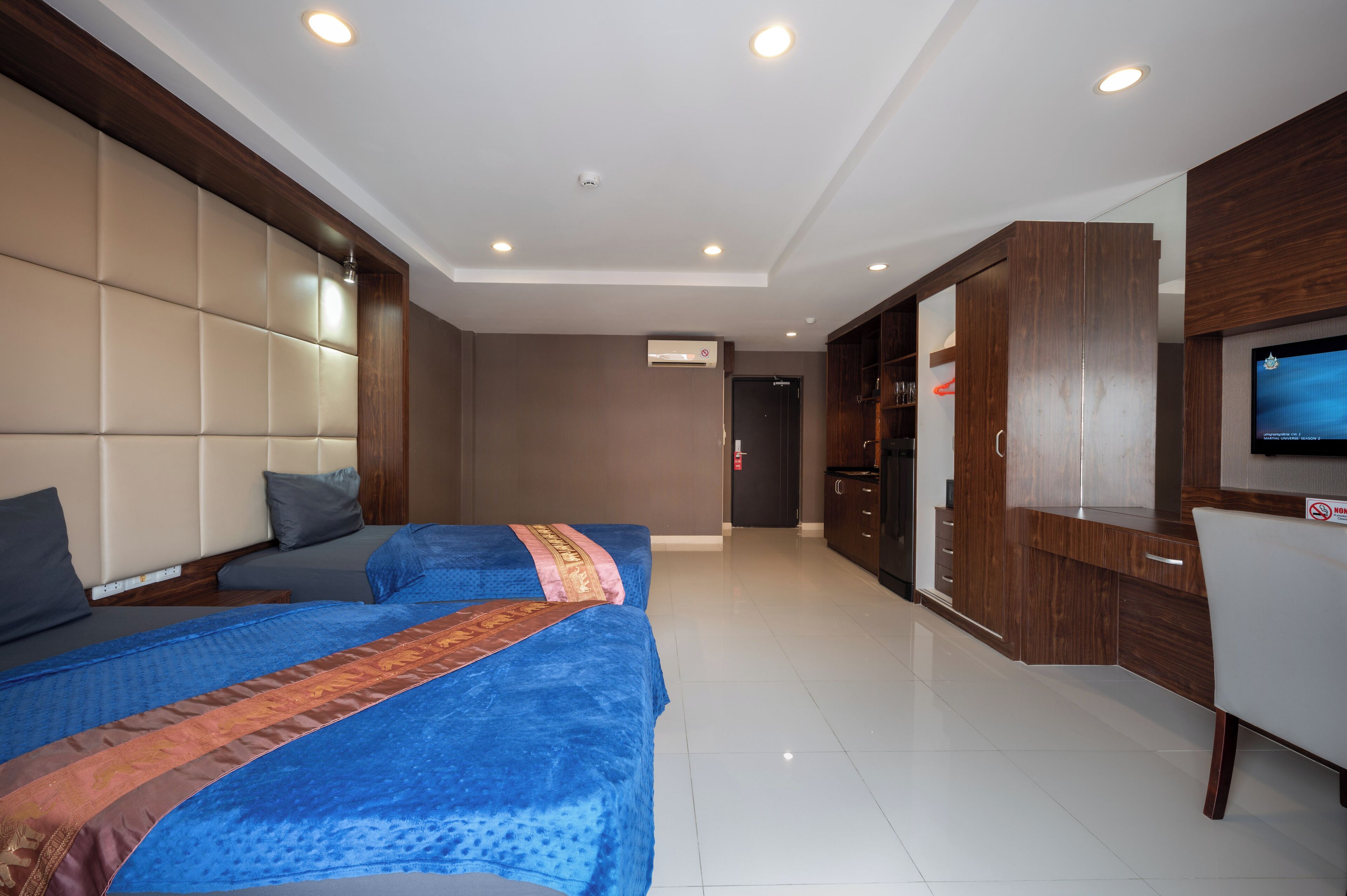 Habitación de hotel con dos camas, televisión, armario y puerta de baño.