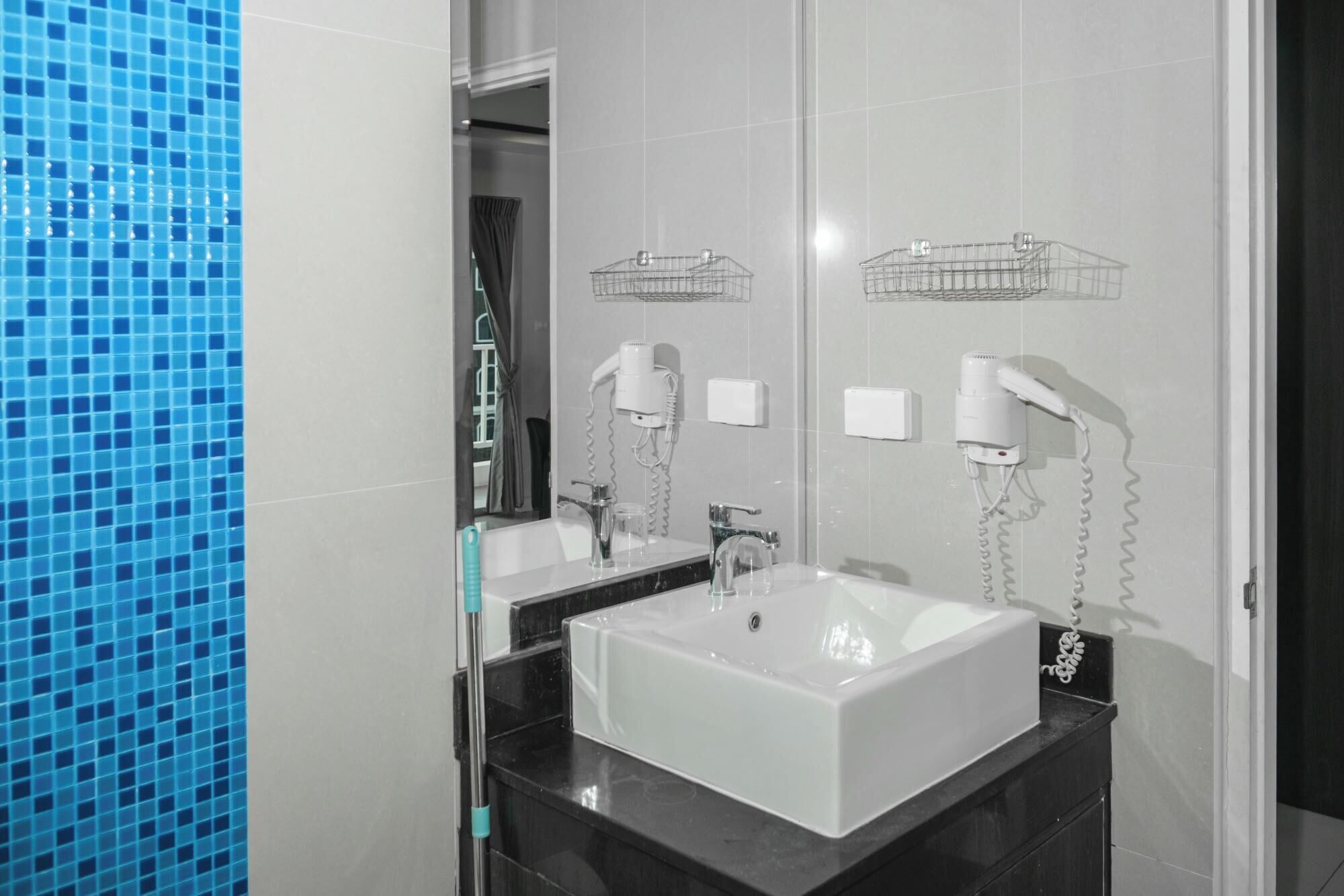 A modern bathroom with a white sink, two mirrors, and two hair dryers mounted on the wall.