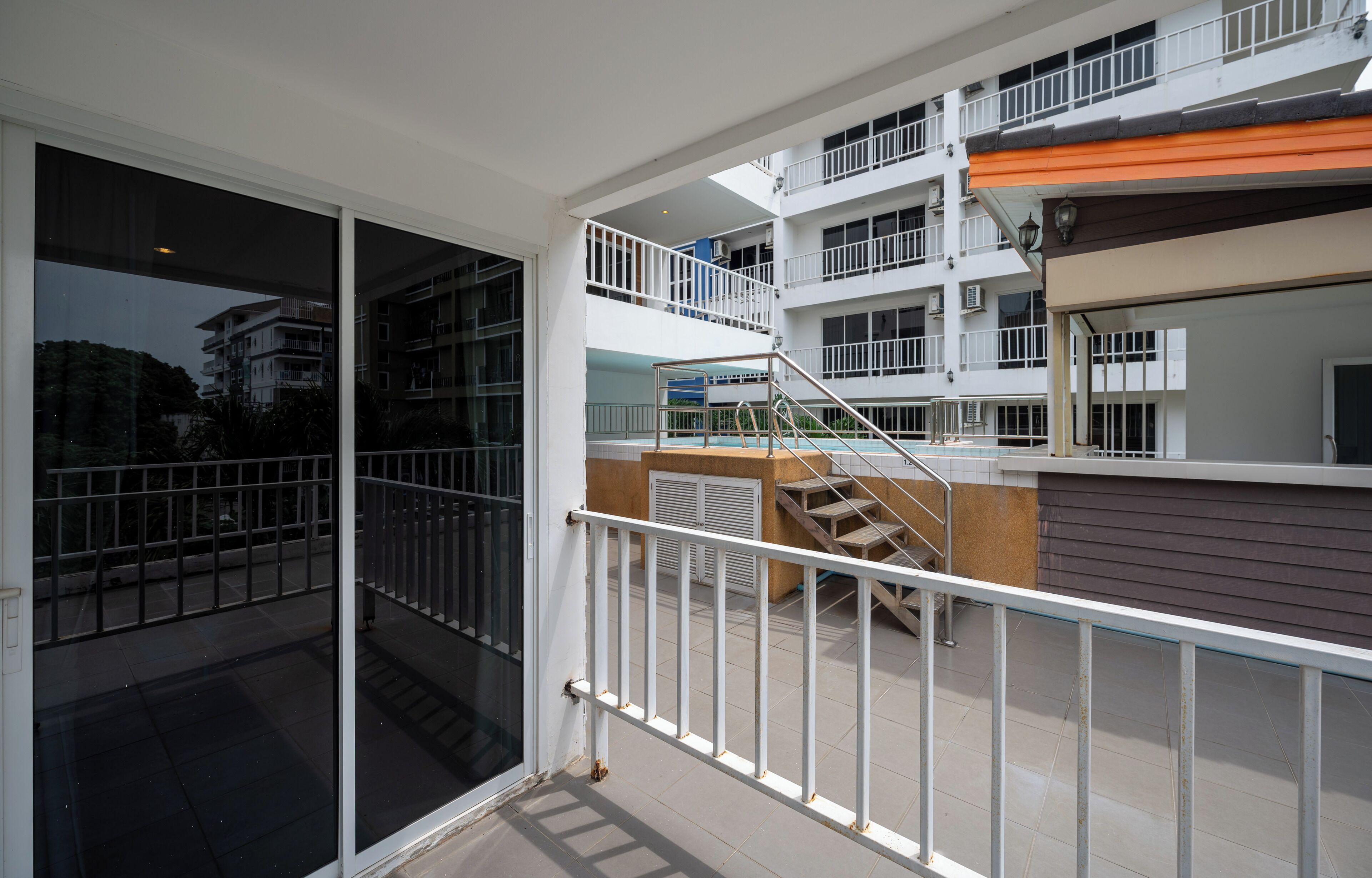 Un immeuble d’appartements moderne doté de nombreux balcons, d’une entrée avec porte vitrée et d’un escalier menant aux étages supérieurs.