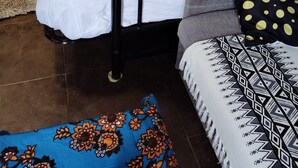 Un lit superposé avec une literie blanche, un coussin à motifs et un tapis bleu.
