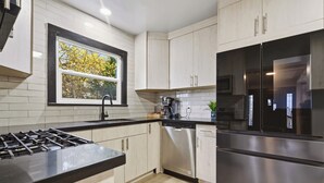 Una cocina moderna con armarios blancos, un refrigerador de acero inoxidable y un lavavajillas.