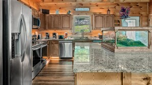 A modern kitchen with stainless steel appliances, wooden cabinets, and a granite countertop. - Elegant Elite Estate By Ghosal Luxury Lodging (Pigeon Forge)