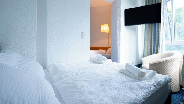 Une chambre d’hôtel avec deux lits, un téléviseur fixé au mur et une chaise.